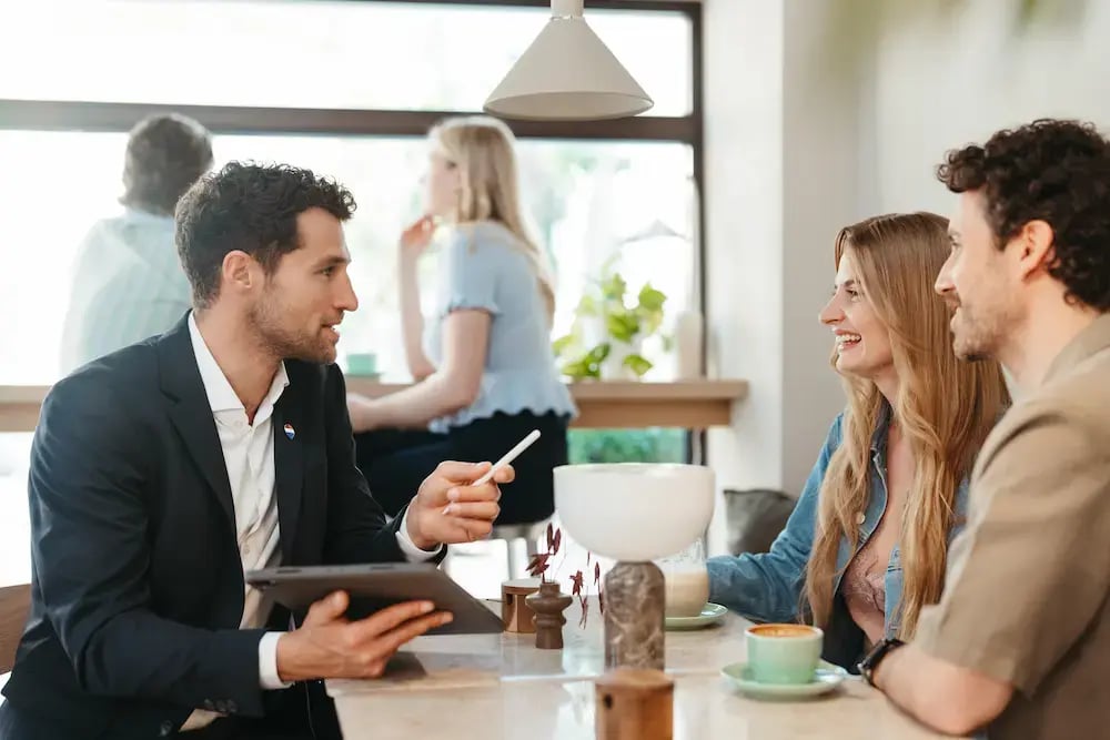 Consulente immobiliare illustra soluzioni abitative digitali a una coppia tramite tablet